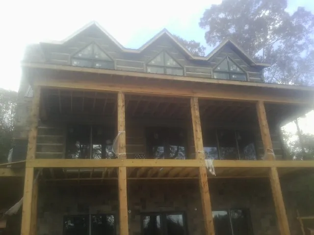 Dormers and porch framing on a large log home under construction — Roof Coating work by our crew in Atlantic