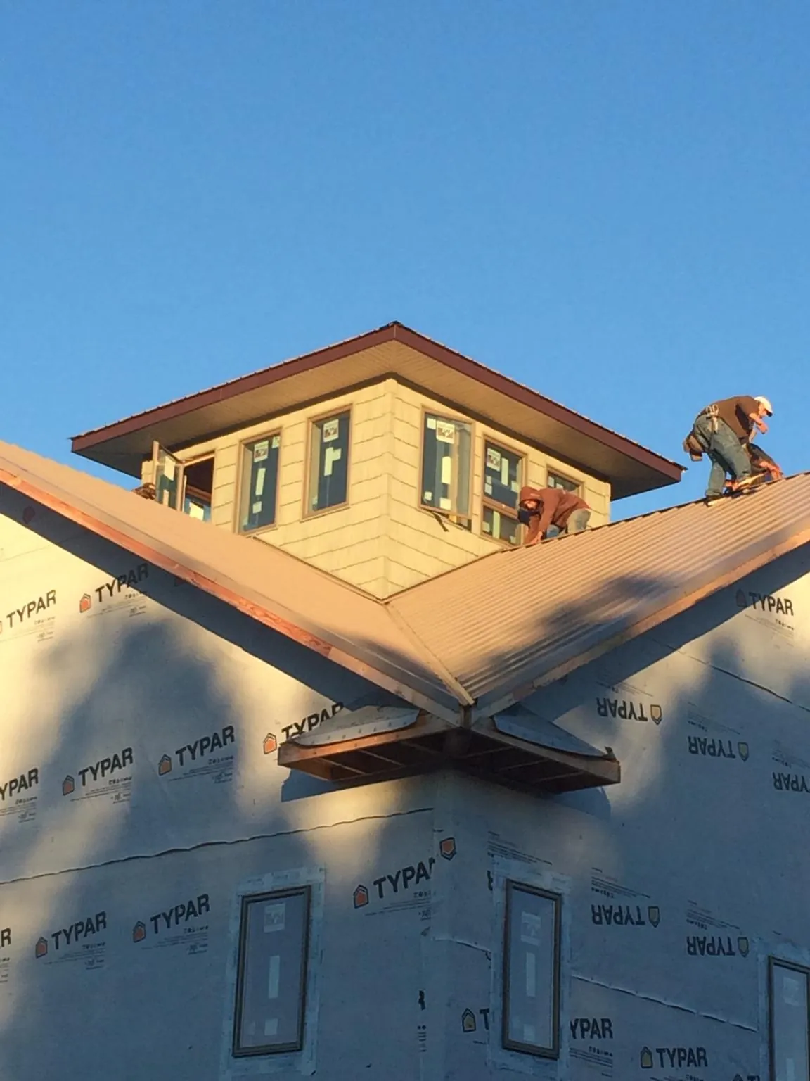 Roofers working around a rooftop cupola on a new metal roof at sunset — Roof Waterproofing in Atlantic by Roofing Brothers